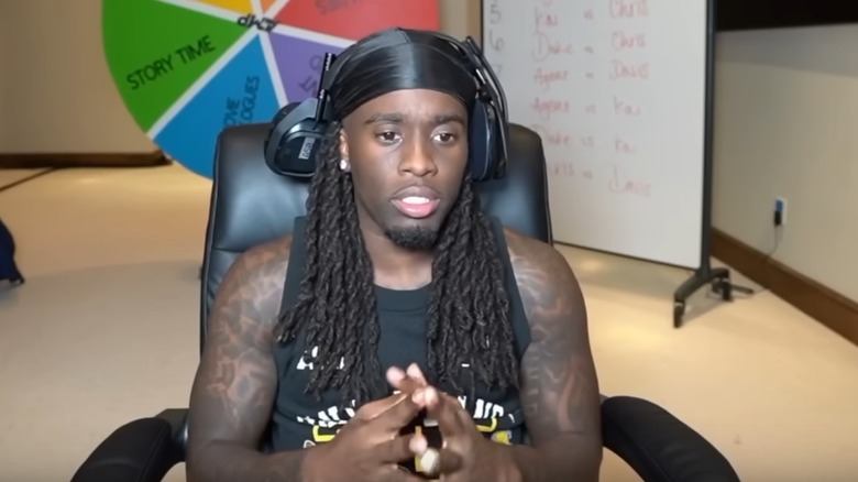 Kai Cenat wearing headphones and sitting in computer chair