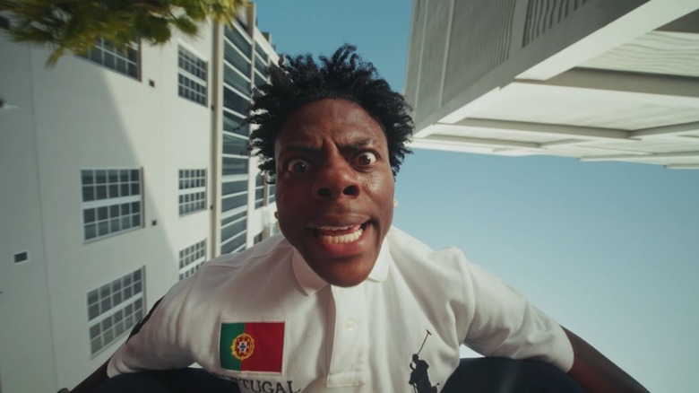 IShowSpeed looking down at the camera wearing a white polo shirt