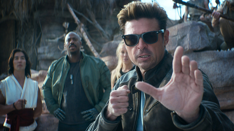 Johnny Cage strikes a fighting pose as Liu Kang, Jax Briggs, and Sonya Blade watch in Mortal Kombat II